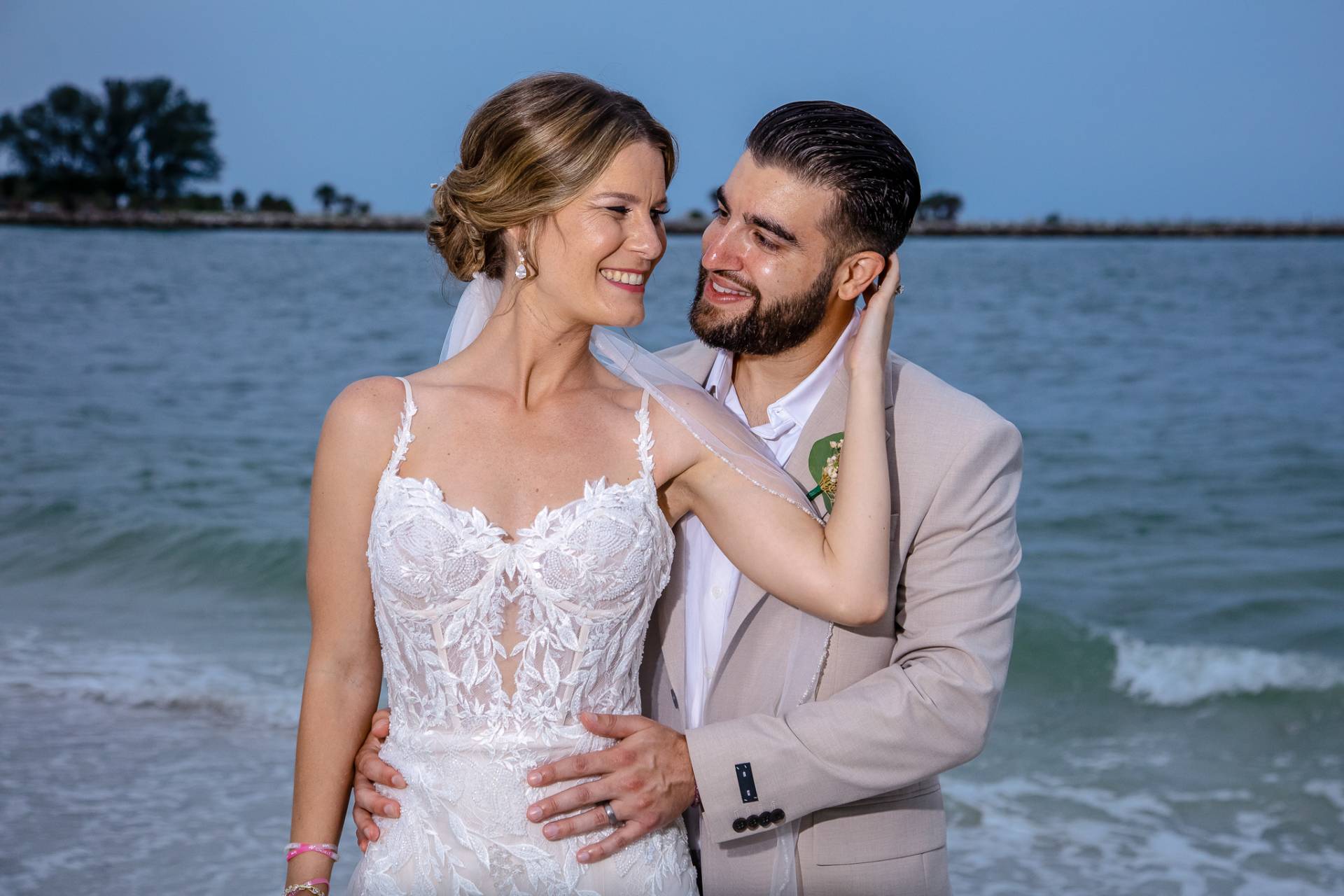 bride and groom looking at each other standing on the beach at sunset