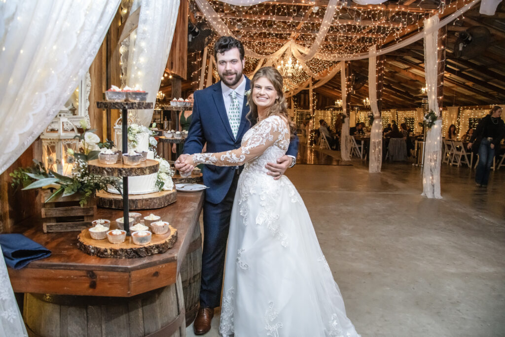 bride and groom cutting their wedding cake inside a barn