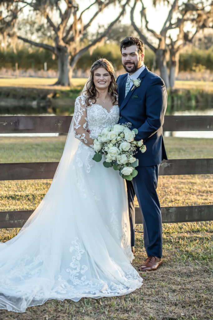 bride resting her head on the groom on front of a wooden fence