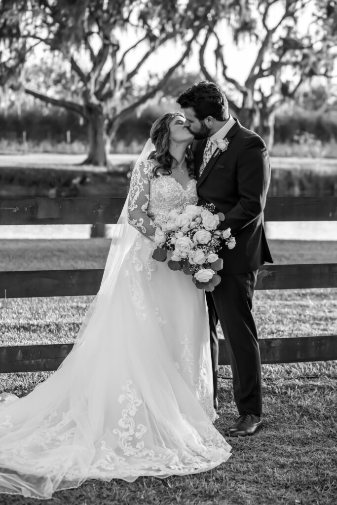 bride and groom kissing in front of a wooden fence