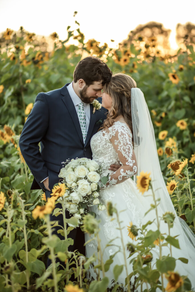 bride and groom with their heads together in the middle of a sunflower field