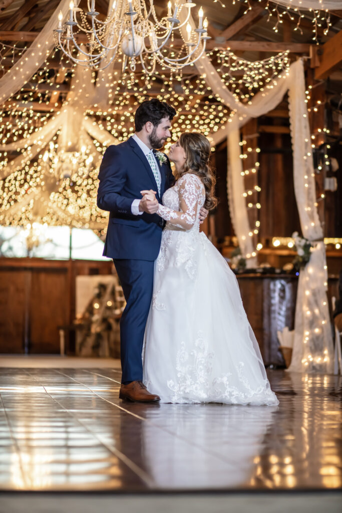 bride and grooms first dance inside of a barn