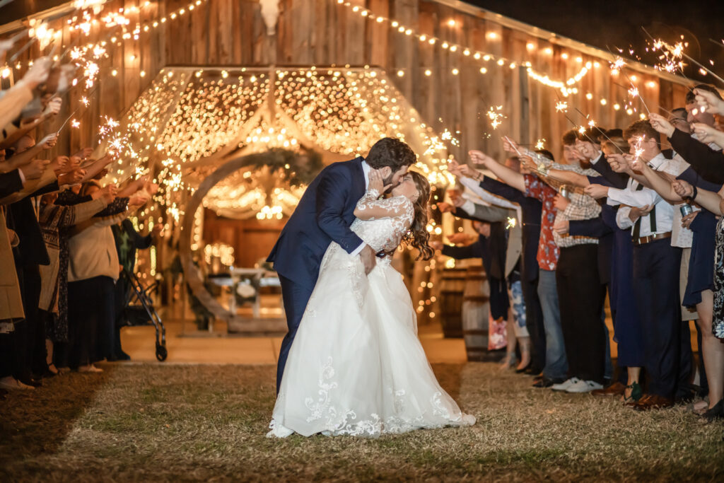 bride and groom exiting a barn with guests holding sparklers