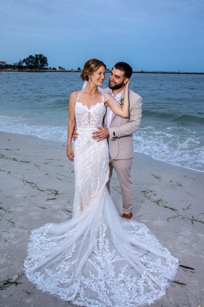 bride and groom looking at each other standing on the beach at sunset