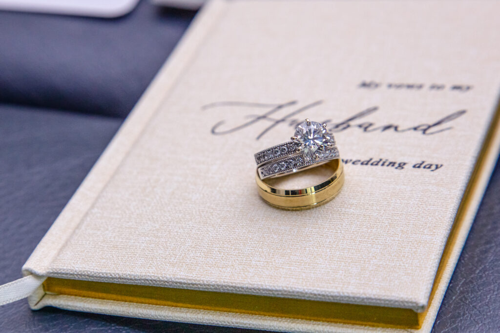 bride and grooms rings sitting on top of the brides vow book