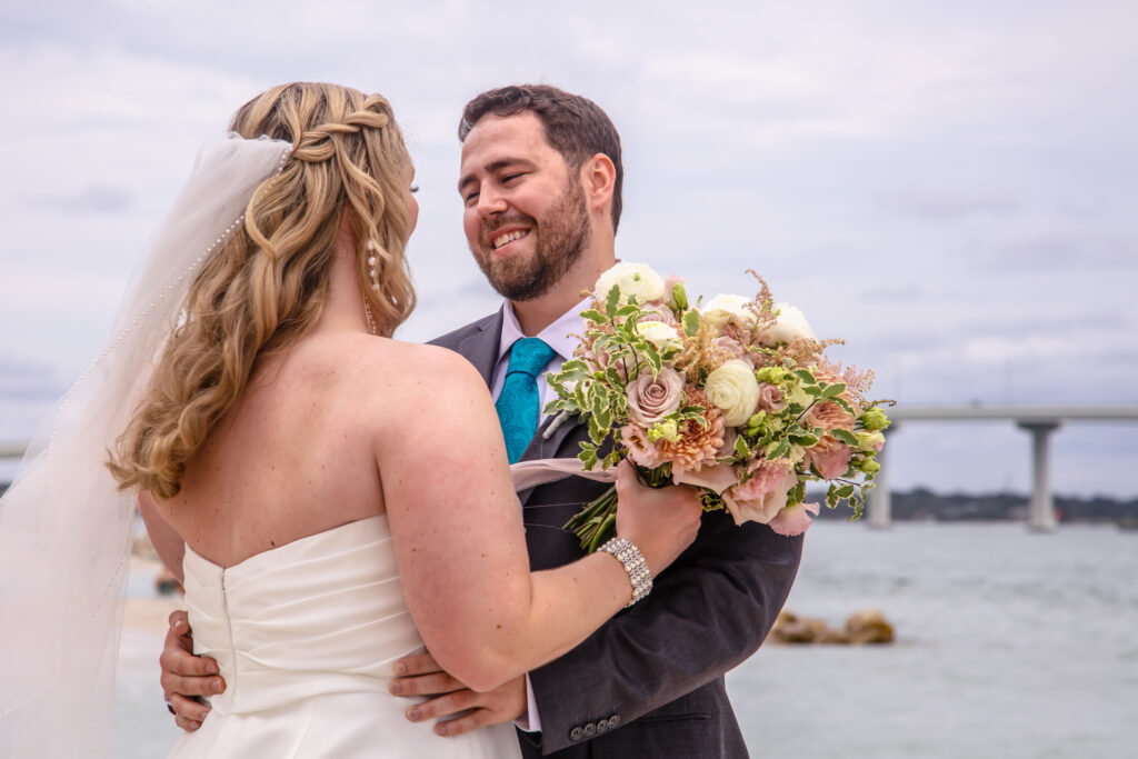 groom smiling at the bride on the beach