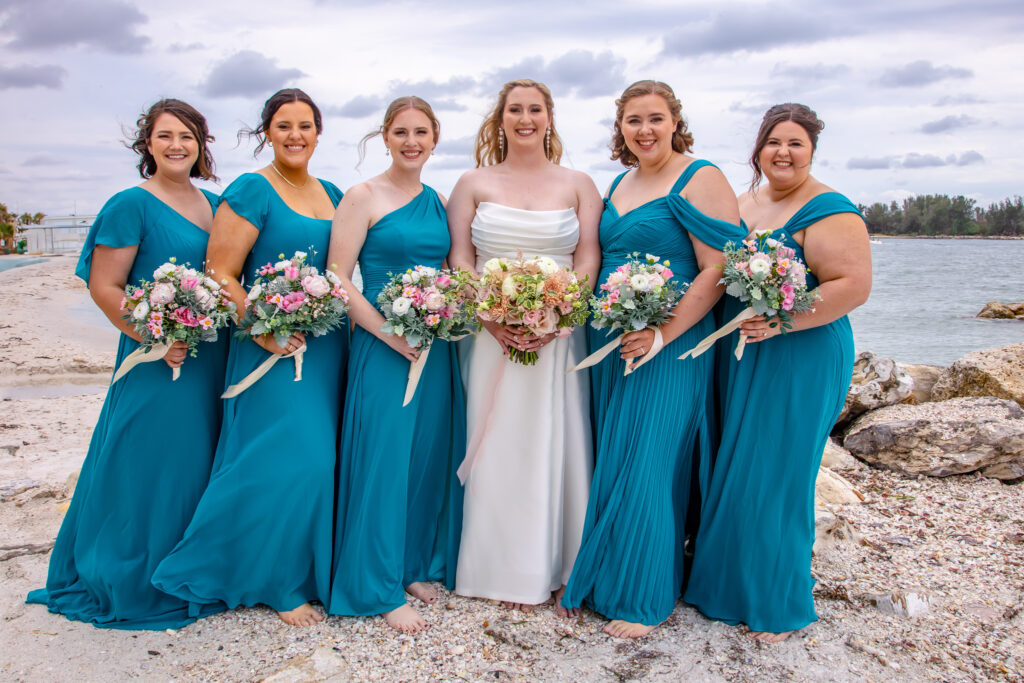 bride with her bridesmaids and their flowers on the beach