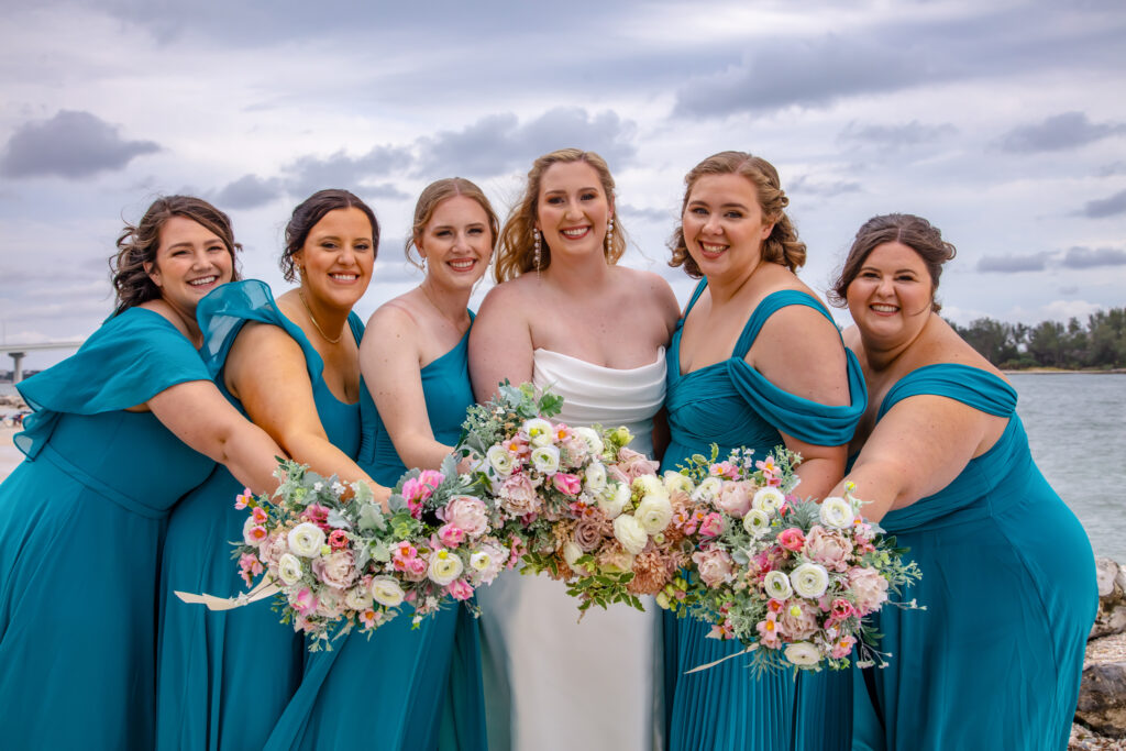 bride with her bridesmaids and their flowers on the beach