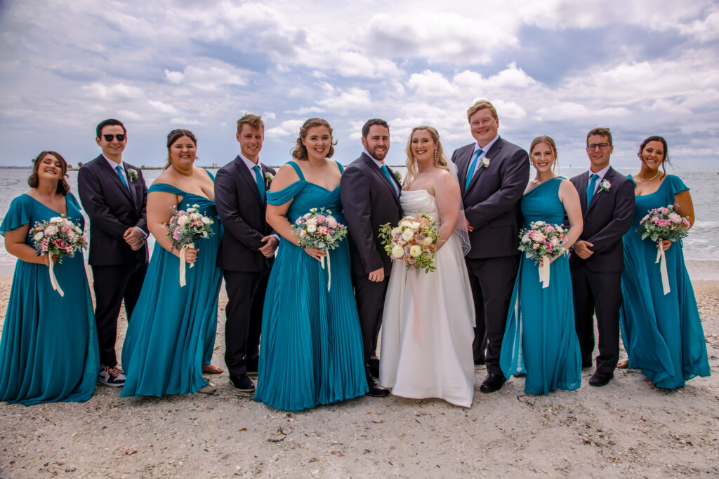 bride and groom with their bridal party on the beach