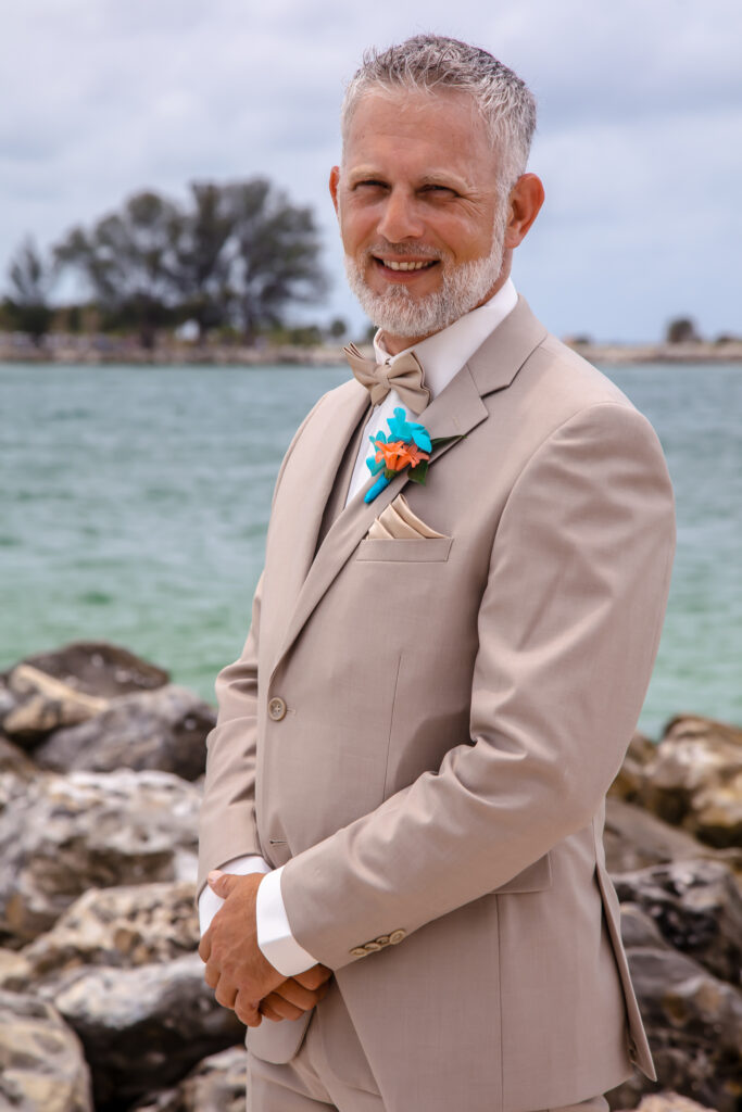 groom standing on the rocks on the beach