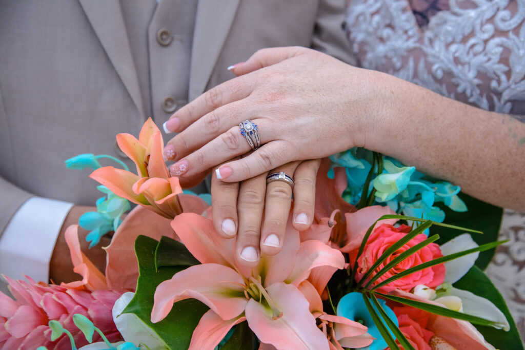bride and groom's ring fingers laying on top of the brides flowers