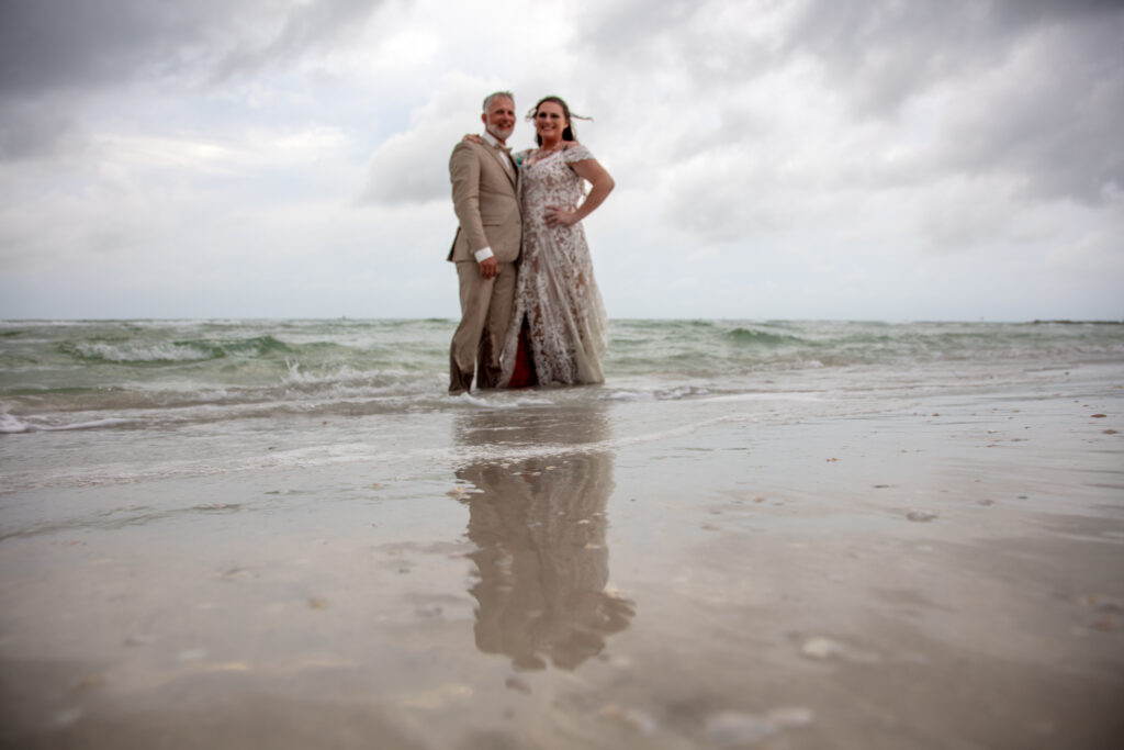 bride and groom standing in the ocean