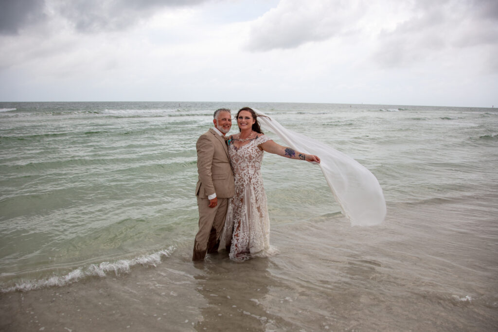 bride and groom standing in the ocean