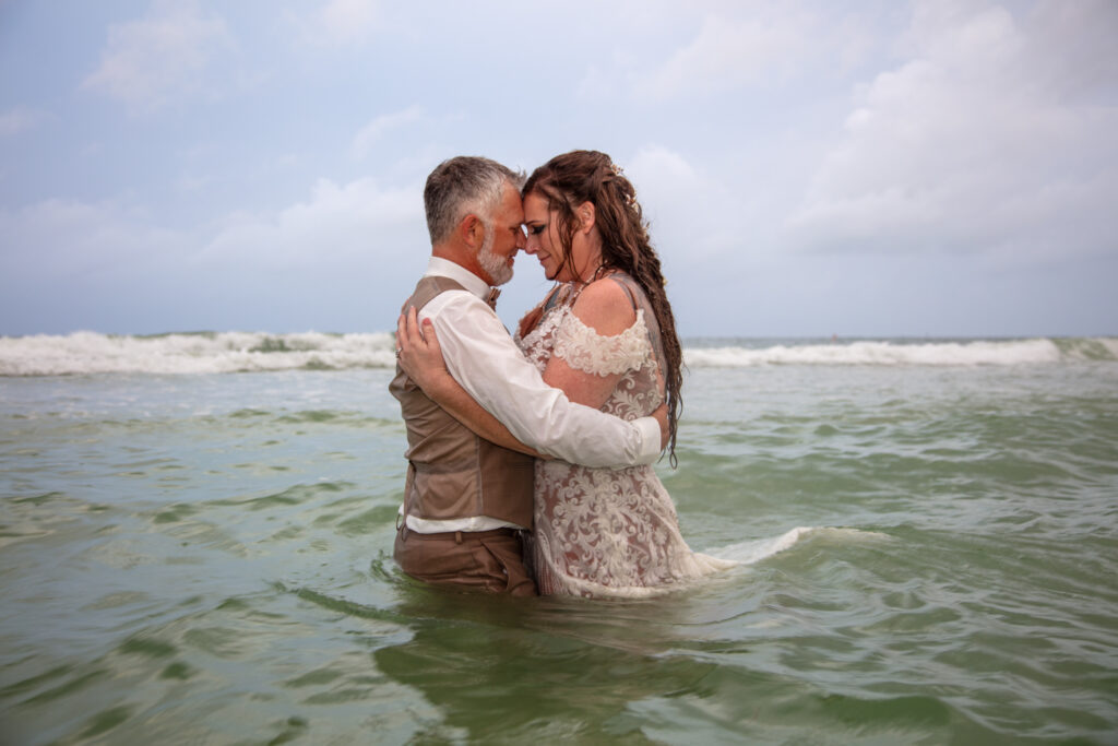 bride and groom standing in the ocean