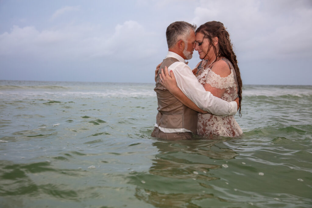 bride and groom standing in the ocean