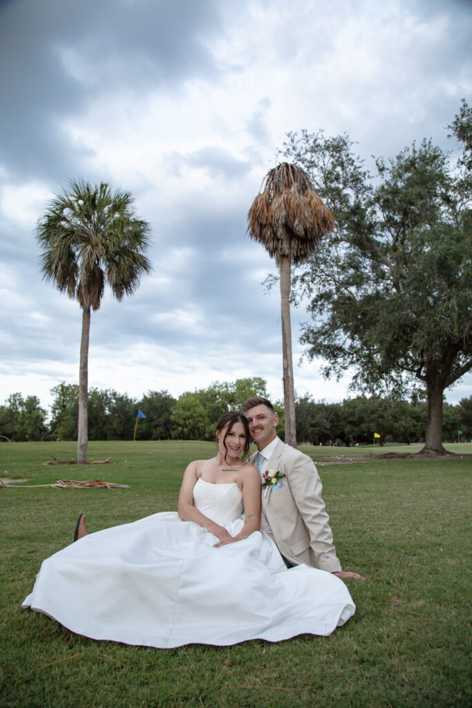 bride and groom sitting on the golf course green